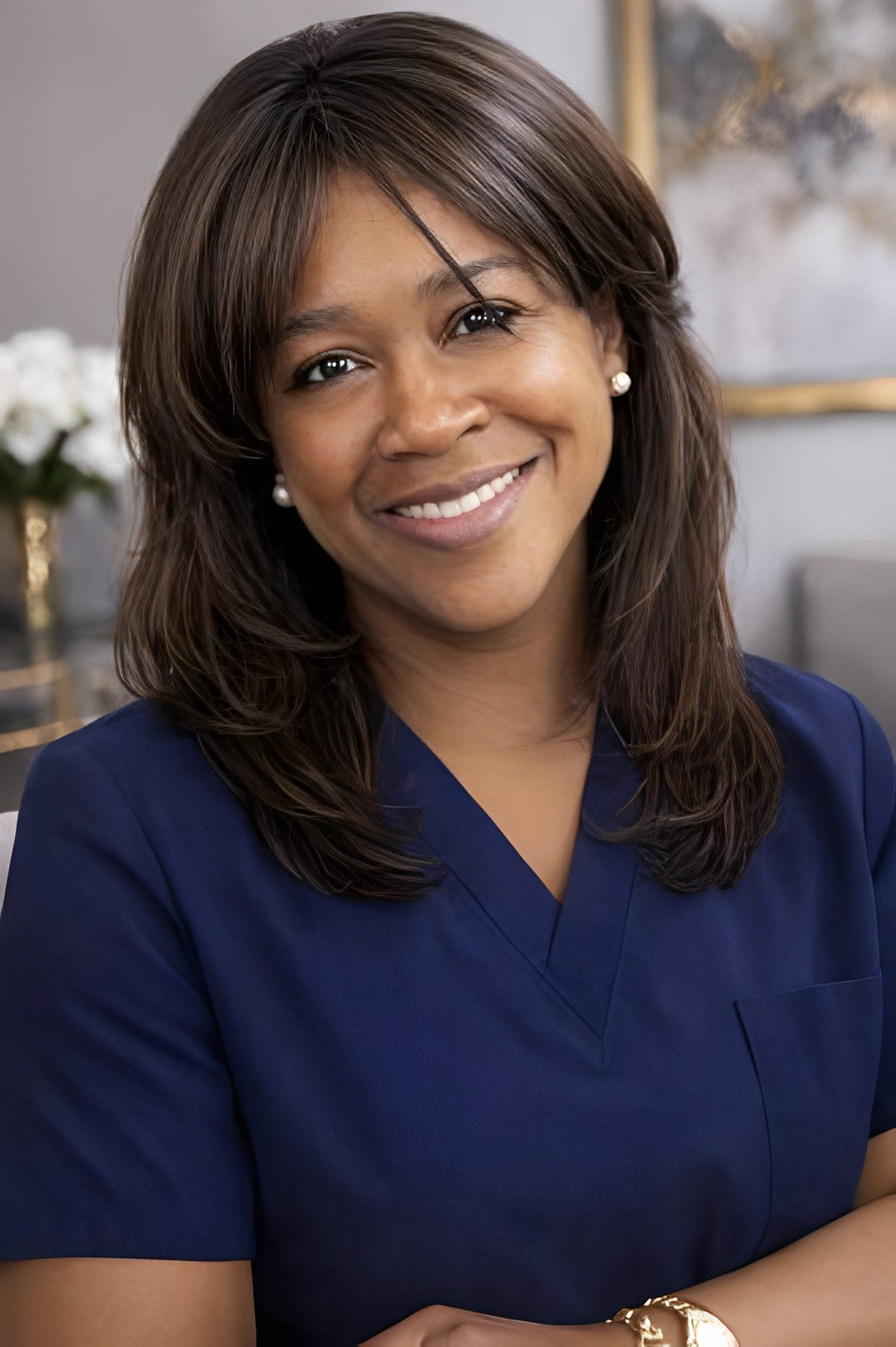 Smiling woman in navy blue scrubs in a professional setting.